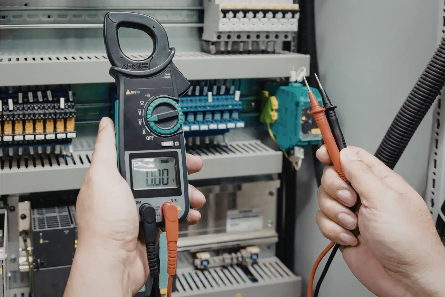 Électricien Qualifelec vérifiant la conformité d'une installation électrique avec un multimètre